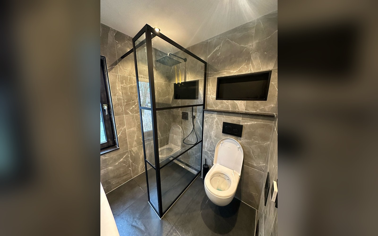 Toilet achter glazen wand met marmerlook tegelwerk